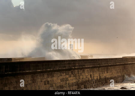 De fortes vagues se briser contre pier avec intéressant fin de journée lumière filtre à travers les nuages et l'humidité. Porto, Portugal, en janvier. Banque D'Images