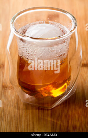 Whiskey soda servi dans un whisky double paroi en verre, servi avec une sphère de glace servi sur une barre en bois haut Banque D'Images