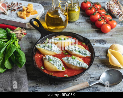 Pâtes cuites conchiglioni farcie épinards et fromage, sauce tomate Banque D'Images