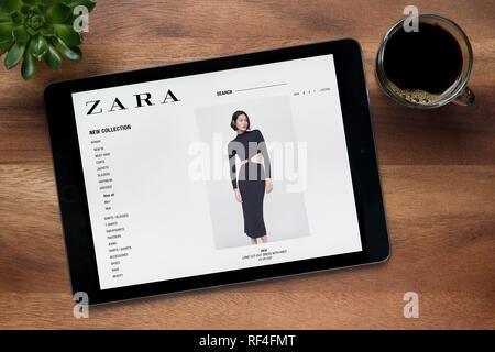 Le site de Zara est vu sur un iPad tablet, sur une table en bois avec une machine à expresso et d'une plante (usage éditorial uniquement). Banque D'Images