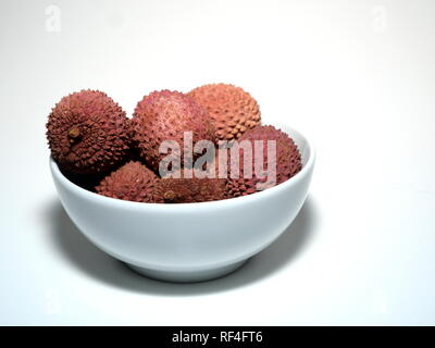 Plusieurs fruits litchi, dans un bol blanc, sur un fond blanc Banque D'Images