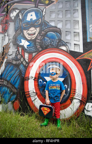 Un jeune garçon dans un costume de super-héro éclectique appuie contre Captain America dans un street art murale dans le quartier de Pilsen Chicago Illinois Banque D'Images