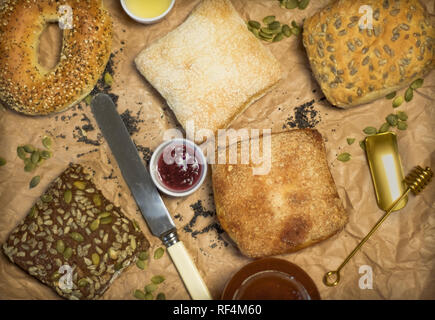 Mettre à plat les petits pains avec de la confiture et le couteau Banque D'Images