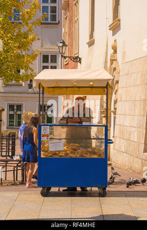 Cracovie, Pologne - 13 juillet 2018. Un vendeur vend Krakowski Obwarzanek de son échoppe sur la rue Grodzka. Il s'agit d'une rue traditionnelle snack - rin tressé Banque D'Images