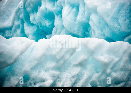 Hornsund | HORNSUND, Svalbard — Des plis et des cavités profonds dans la glace glaciaire montrent où l’eau de fusion a creusé des canaux à travers un iceberg dérivant dans le fjord de Hornsund. De tels fragments de glace se détachent des fronts de calage des six glaciers de marée du fjord, un processus maintenant documenté comme faisant partie de l’un des dossiers d’échauffement le plus rapide de l’Arctique. Banque D'Images