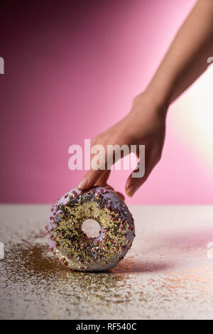 Portrait of woman holding sweet donut avec paillettes d'or sur fond rose Banque D'Images