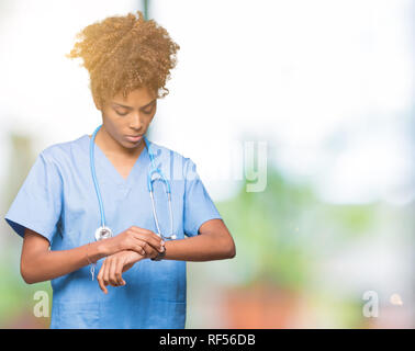 Young african american woman médecin isolé sur le temps de vérification d'antécédents sur montre bracelet, détendu et confiant Banque D'Images