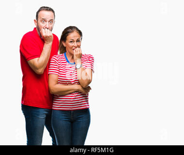 L'âge moyen hispanic couple dans l'amour sur fond isolé à souligné et nerveux avec les mains sur la bouche de mordre les ongles. Problème d'anxiété. Banque D'Images