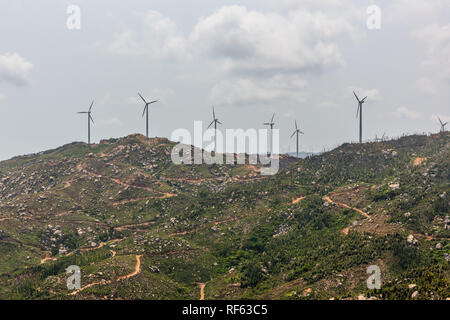 Les éoliennes sur le paysage le long de la route vide contre ciel. Banque D'Images