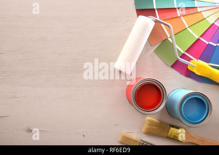 Deux pots de peinture rouge et cyan et la palette ouverte sur table en bois pour la rénovation des matériaux. Vue d'en haut. Composition horizontale. Banque D'Images