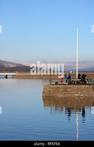 Les gens de la pêche dans la rivière de l'estuaire de Kent à Arnside Pier à marée haute en janvier 2019 avec Arnside viaduc de chemin de fer derrière, Cumbria, Royaume-Uni. Banque D'Images