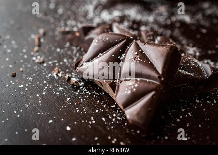 Morceaux de chocolat amer à la fleur de sel sur la surface en bois sombre. Des collations bio.