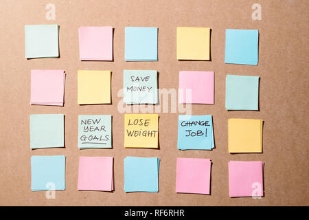 Objectifs de la nouvelle année ou de résolutions - sticky notes colorées sur un bloc-notes avec tasse à café. Banque D'Images