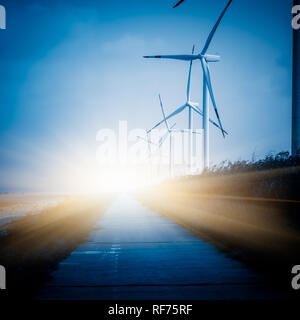Les éoliennes sur le paysage le long de la route vide contre ciel. Banque D'Images
