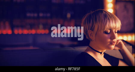 Femme assise sur un canapé en bar Banque D'Images