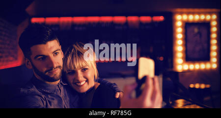 Couple sur téléphone mobile en selfies bar Banque D'Images
