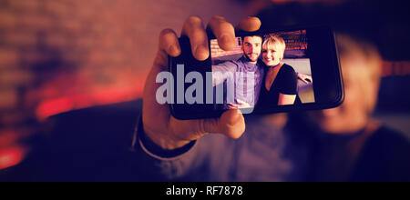 Couple sur téléphone mobile en selfies bar Banque D'Images