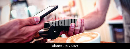Close-up of customer with cellphone et barista avec lecteur de carte Banque D'Images