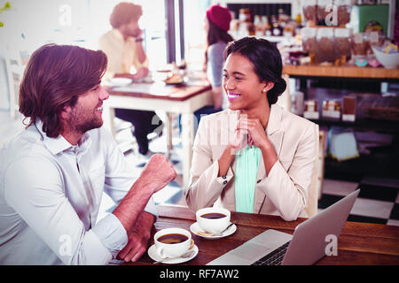 Sourit l'homme et de la femme à l'aide d'un ordinateur portable tout en ayant tasse de café Banque D'Images
