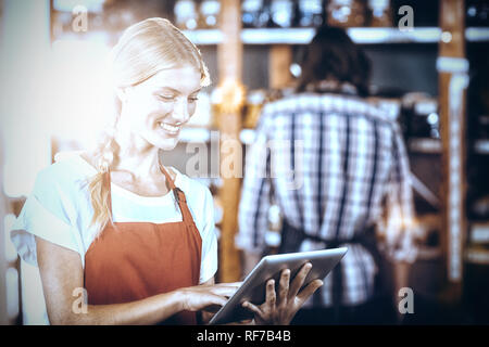 Le personnel féminin using digital tablet in supermarket Banque D'Images