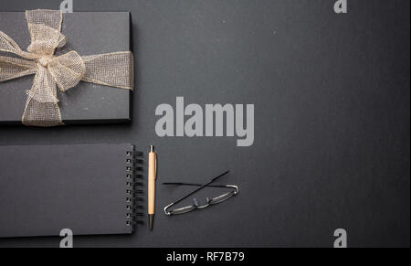 Fête des Pères, Noël au travail. Boîte cadeau noir avec ruban noir brillant sur Office 24, Vue de dessus, copy space Banque D'Images