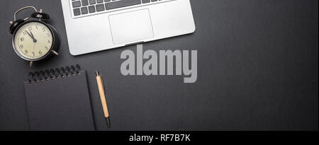 Concept de gestion du temps. Ordinateur portable et réveil sur la couleur noire, la bannière de bureau, vue du dessus, copy space Banque D'Images