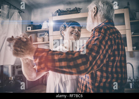 Senior couple dancing together in kitchen Banque D'Images