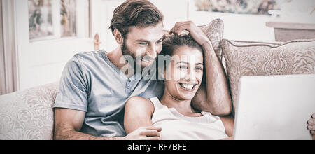 Couple sitting on sofa and using laptop Banque D'Images