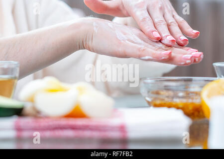 La femme l'application de la crème sur ses mains hydratant et nourrissant avec les cosmétiques naturels close-up. Concept d'hygiène et de soins pour la peau Banque D'Images