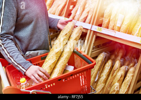 Acheteur avec des baguettes de pain avec un panier de provisions dans le magasin Banque D'Images