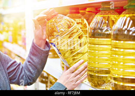 Grande bouteille en plastique d'huile d'olive dans la main de l'acheteur à l'épicerie Banque D'Images