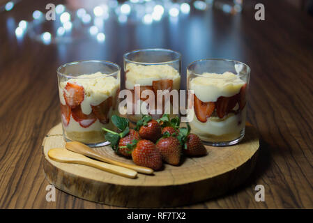 Le dessert appelé Magnolia décoré de lumières. Préparé avec de la crème, des biscuits et des fraises. Servi sur la plaque de bois. Banque D'Images