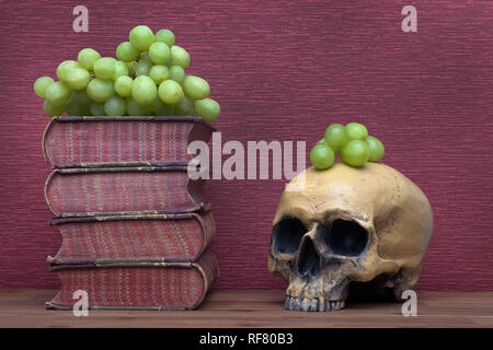 Livres Anciens, crâne humain et raisins sur le fond de la bourgogne. Banque D'Images