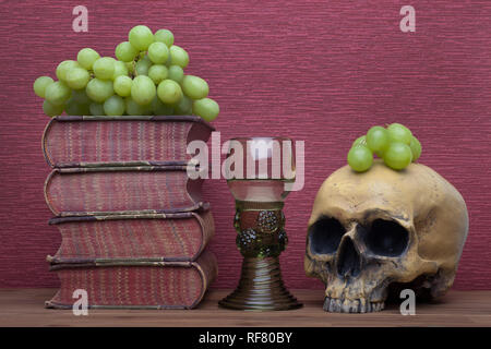 Renaissance, rummer verre vin, de vieux livres, crâne humain et raisins sur le fond de la bourgogne. Banque D'Images