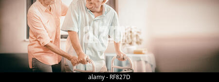 Senior woman aidant les homme à marcher avec walker Banque D'Images