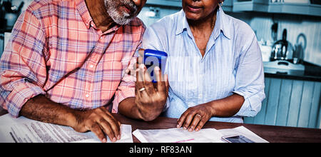 Couple using calculator en discutant par rapport au document Banque D'Images