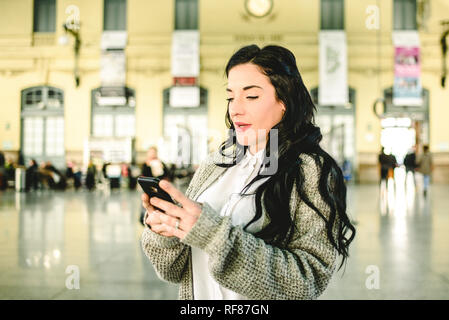 Belle femme mature contrôler les horaires de son train sur son téléphone mobile. Banque D'Images