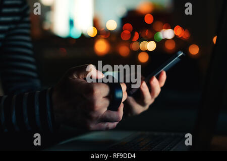 Woman with coffee cup looking at smartphone à écran nuit close up of hands Banque D'Images