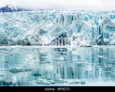 Glacier Lilliehöökfjorden Svalbard Norvège / SPITZBERG, Svalbard — la face de vêlage de Lilliehökbreen est vue depuis le niveau de l'eau à Lilliehöökfjorden, avec des icebergs flottant au premier plan contre l'imposante paroi de glace se dressant à environ 130 pieds (40 m) au-dessus de la surface. Le glacier se trouve sur le Spitzberg dans l'archipel du Svalbard et a reculé de plus de 1,5 miles (2,5 km) depuis 2000, modifiant fondamentalement la bathymétrie et la zone d'eau libre du fjord alors que le terminus se retire du contact avec les eaux de marée. Le fjord est situé dans Albert I Land sur la côte nord-ouest du Spitzberg, une région de Re Banque D'Images