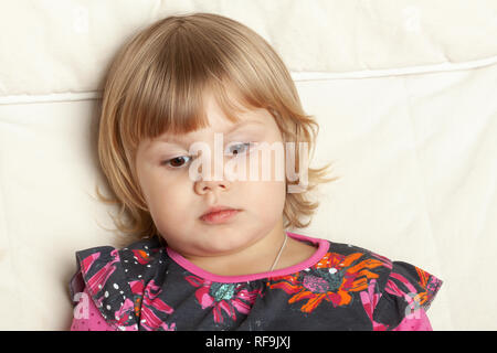 Portrait grave mignon petite fille assise dans la chaise blanche, closeup portrait studio Banque D'Images