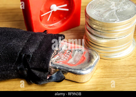 Libre de pièces d'argent d'une once de l'Amérique blanche et pose de brique sur fond de bois avec horloge rouge à l'arrière Banque D'Images