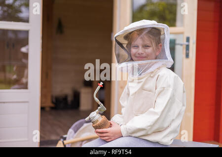 Portrait d'une fillette de 7 ans avec fonction de protection de l'apiculteur les abeilles. Dans sa main elle tient une pipe de l'apiculteur Banque D'Images