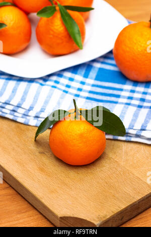 Mandarines Mandarines Clémentines,mûrs sur fond en bois avec une serviette bleue. Banque D'Images