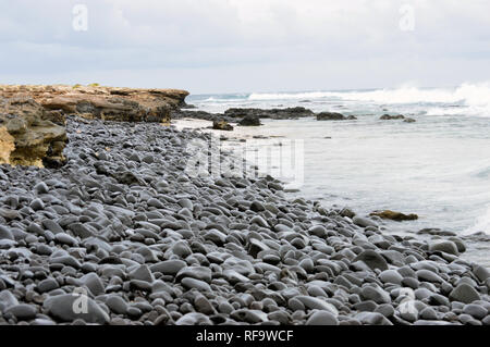 Cailloux volcanique noire sur une plage sur la côte sud de l'île de Boa Vista, Cap Vert, Afrique. Banque D'Images
