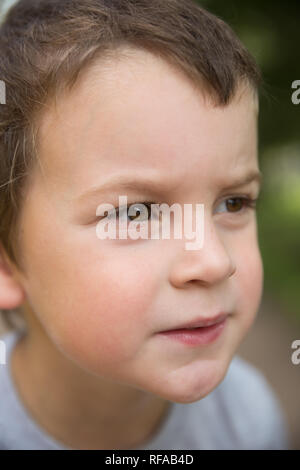 Closeup portrait of a Boy rousseur graves avec les cheveux foncés et les yeux bruns à l'extérieur Banque D'Images