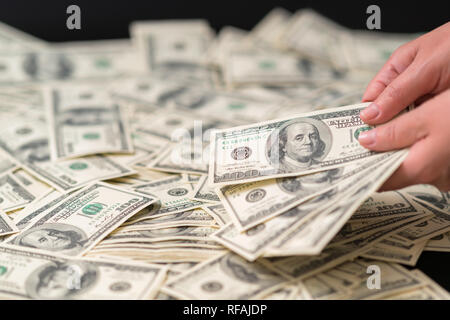 Femme tenant une poignée de billets de 100 USD sur une table parsemée de plusieurs projets de loi dans un concept de succès, la corruption, l'administration et les finances Banque D'Images