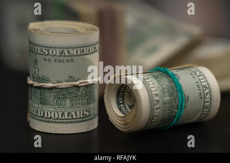 Deux rouleaux de factures USD laminées à égalité avec les bandes de caoutchouc l'une verticale et l'autre sur le côté, sur un tableau noir dans une image conceptuelle ou la corruption financière Banque D'Images