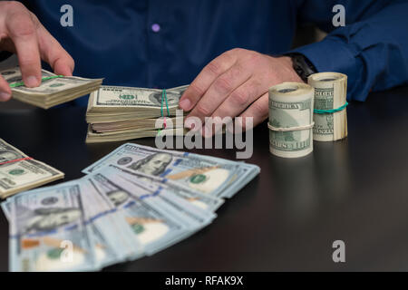 De paiement en espèces ou d'offrir un pot-de-remise des piles de 100 dollar bills à travers une table dans un gros plan sur les mains Banque D'Images