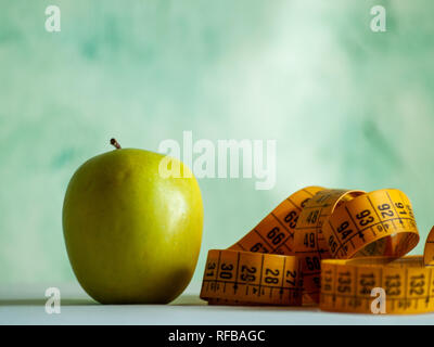 Concept de l'obésité. Une pomme verte et d'un ruban de mesure sur une table Banque D'Images