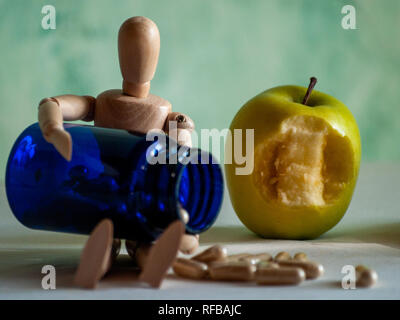 Une figurine en bois avec un piqué et un conteneur bleu apple avec la fibre végétale comprimés sur une table Banque D'Images